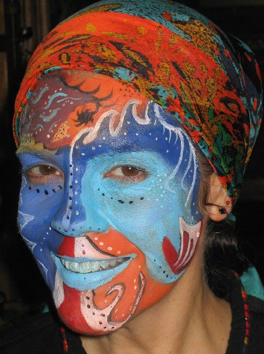 A woman with her face painted has a scarf around her head