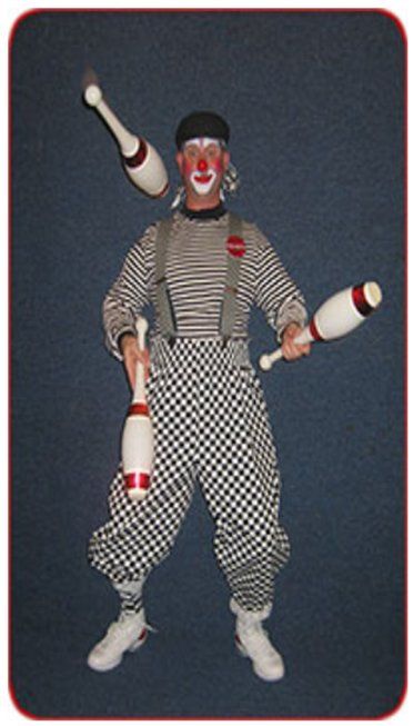 A man in a clown costume is juggling three clubs