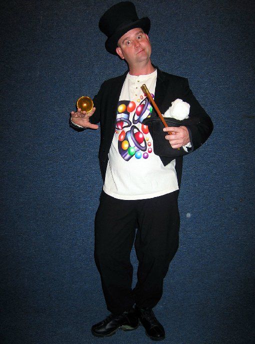 A man in a top hat is holding a trumpet and a wand