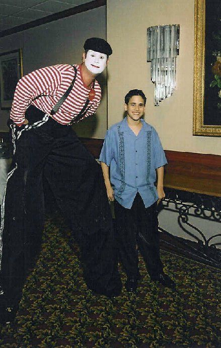 A man on stilts is standing next to a boy in a blue shirt