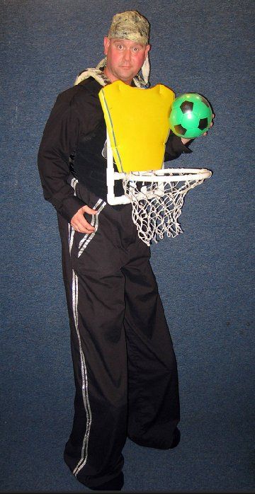 A man is holding a soccer ball in front of a basketball hoop