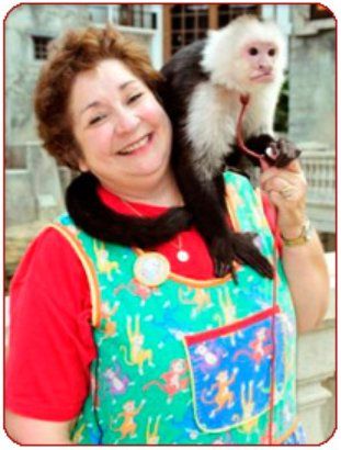 A woman is holding a small black and white monkey on her shoulder