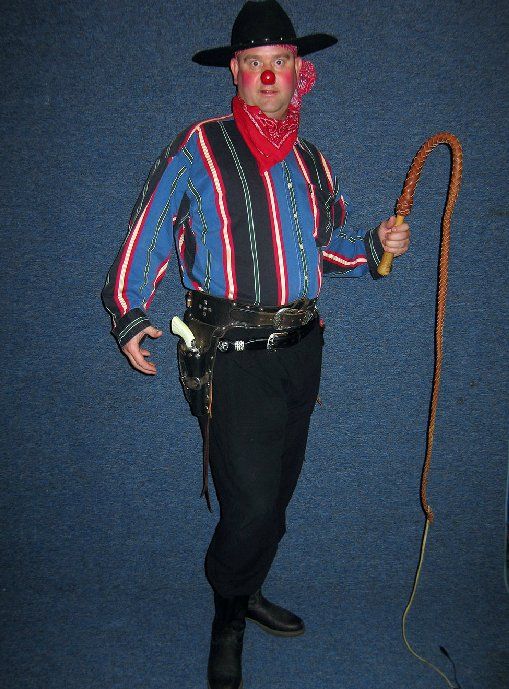 A man in a cowboy costume is holding a whip