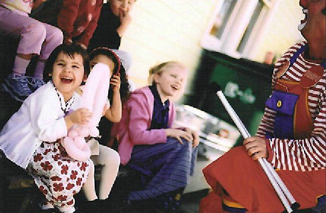 A group of children are sitting around a clown