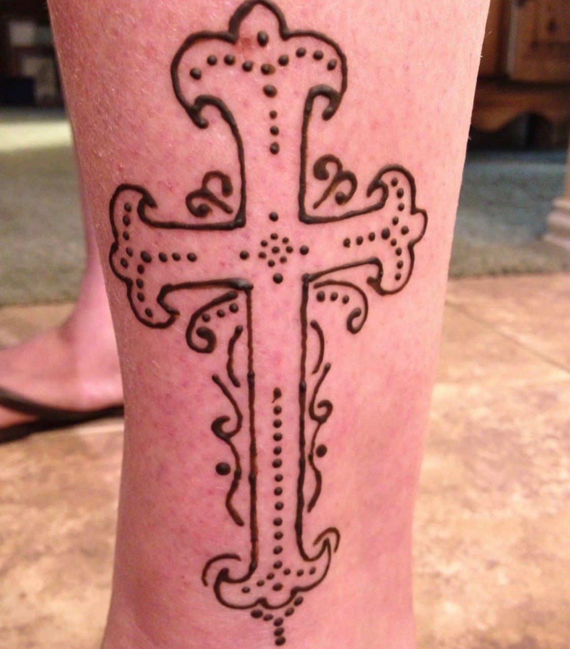 A person has a cross tattoo on their leg