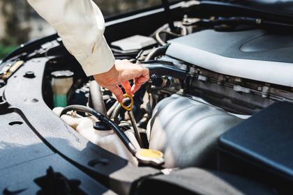 Una persona sta controllando il livello dell'olio nel motore di un'auto.