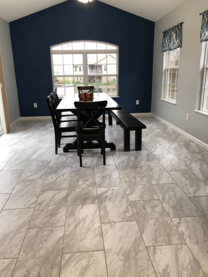 Dining room with dark blue accent wall, large window, marble-look floor, and black table set.