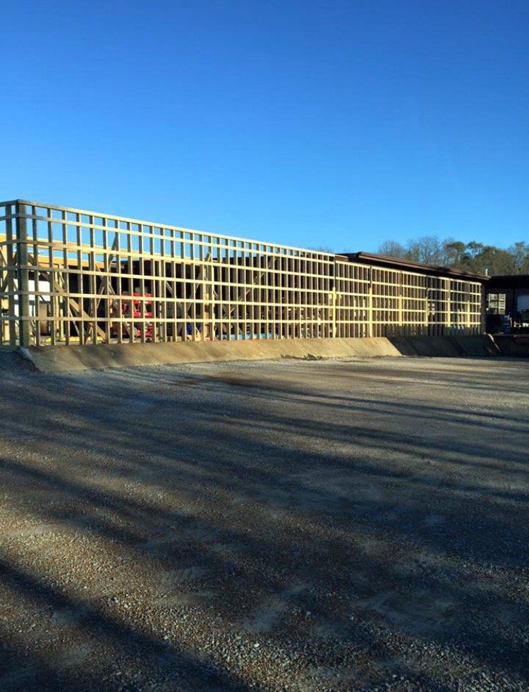 Long wooden fence along a paved path under a clear blue sky, with shadows cast across the ground.