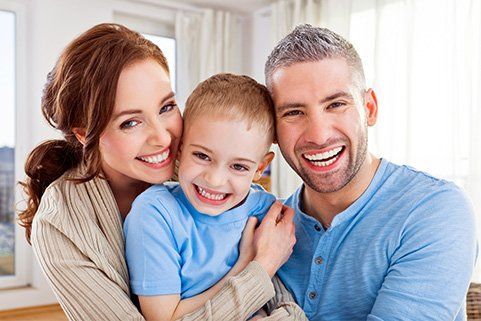 A happy family is posing for a picture together in a living room.