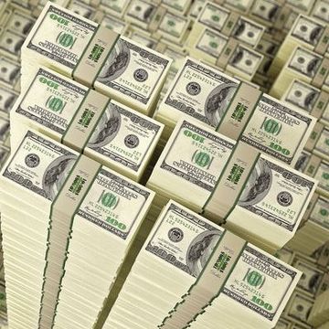 Stacks of U.S. hundred-dollar bills arranged in a pile on a surface.