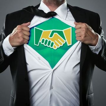Man in black suit revealing green shirt with white handshake icon like a superhero emblem