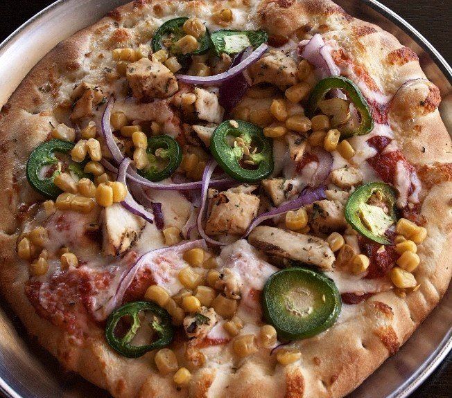 A pizza with chicken jalapenos corn and onions on it
