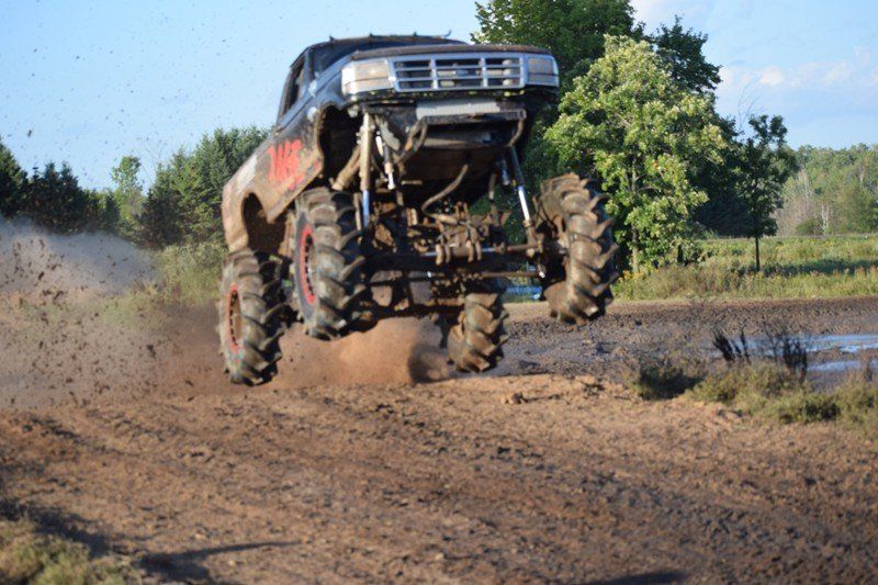Off-road truck with raised suspension splashing through a muddy dirt track