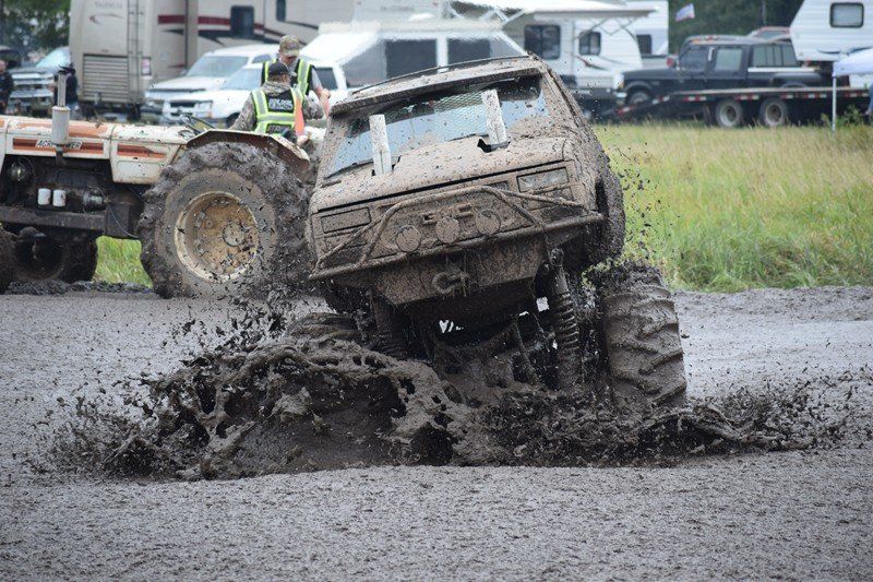 Mud-covered off-road vehicle stuck in a muddy pit at a race track