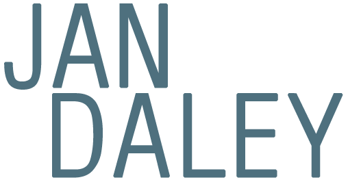The logo for jan daley is blue and white on a white background.