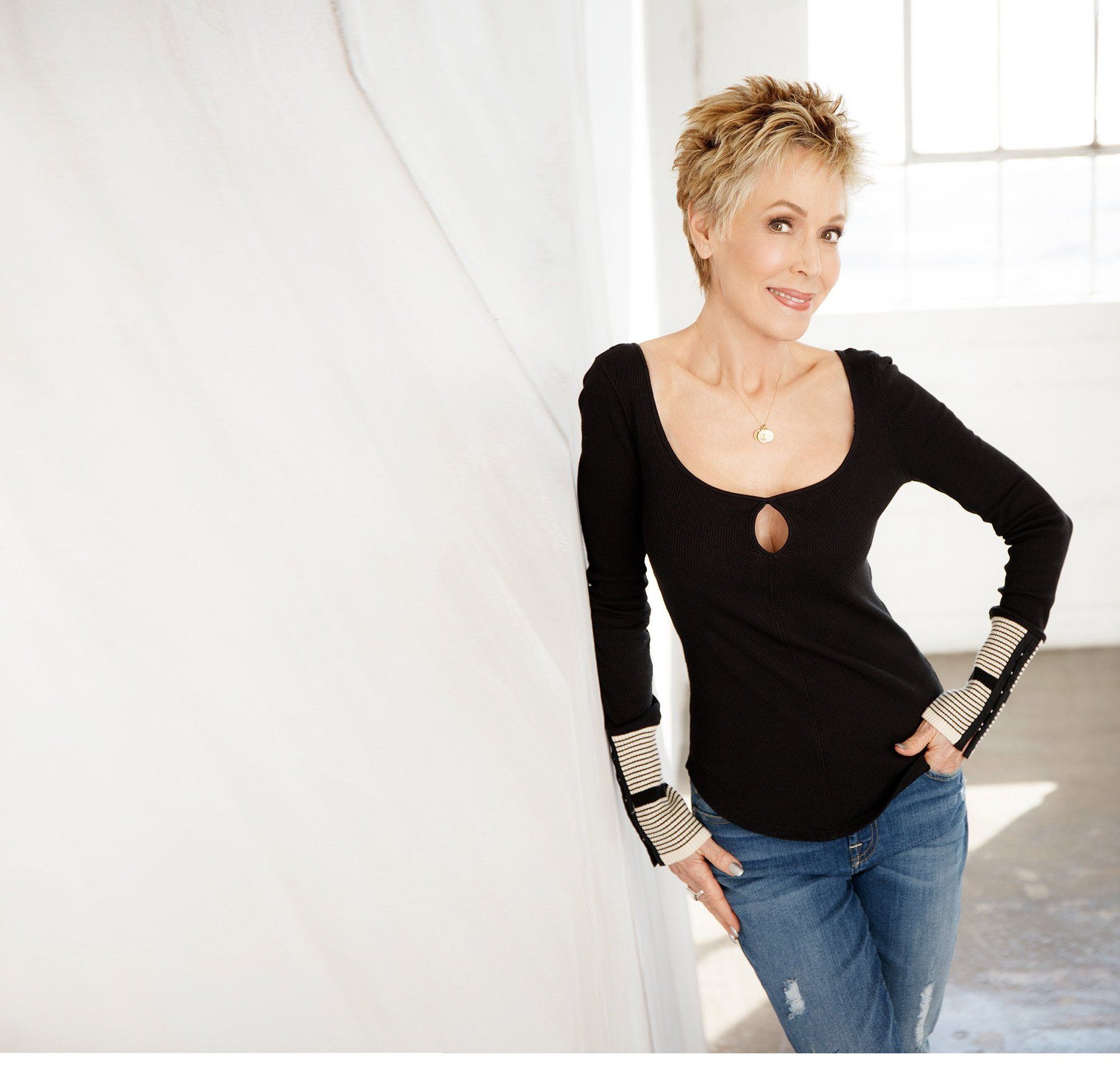 A woman leaning against a wall with her hands in her pockets