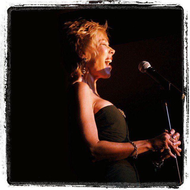 A woman singing into a microphone in a dark room
