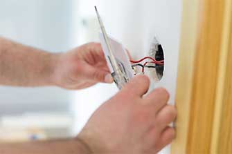 Handy man installing light switch after home renovation — Electric Contractors in Portland, Maine Handy man installing light switch after home renovation — Electric Contractors in Portland, Maine
