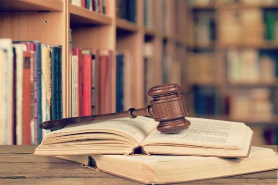 il martello della giustizia su alcuni libri in una stanza piena di scaffali con libri il martello della giustizia su alcuni libri in una stanza piena di scaffali con libri