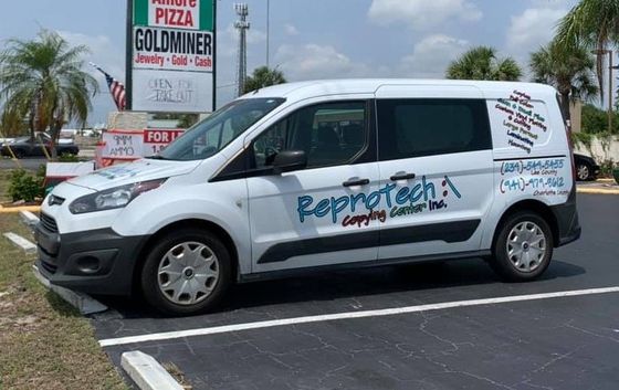 White Reprotech van parked in a lot, with logo on side. Sign for
