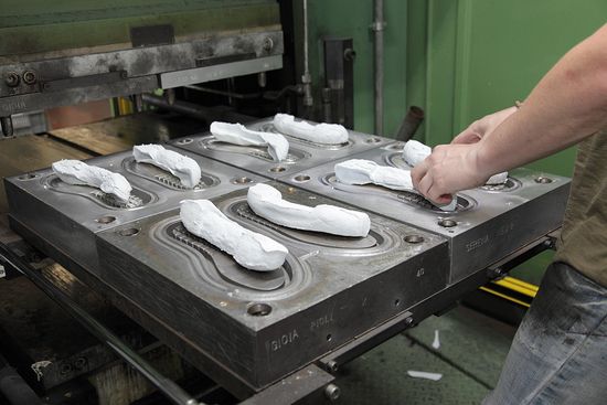 Artigiano incolla la suola alla tomaia di una scarpa da uomo