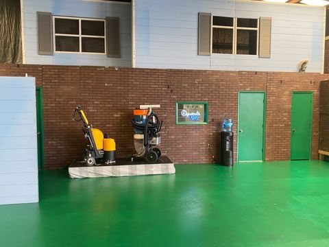 A room with a green floor , a brick wall , and a vacuum cleaner.
