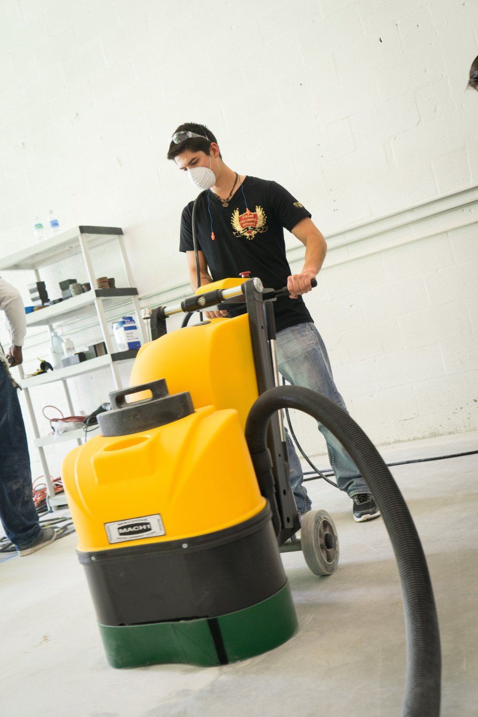 A man wearing a mask is using a yellow vacuum cleaner