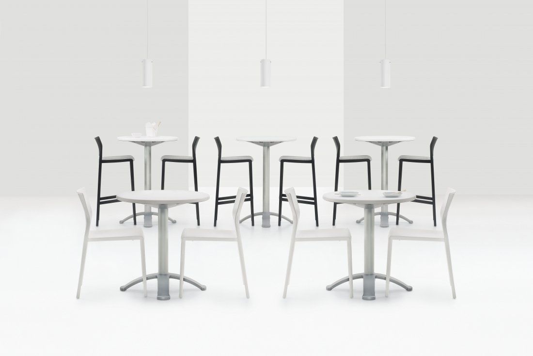 Cafe setting: white chairs and tables, black bar stools, overhead lights, minimalist design.