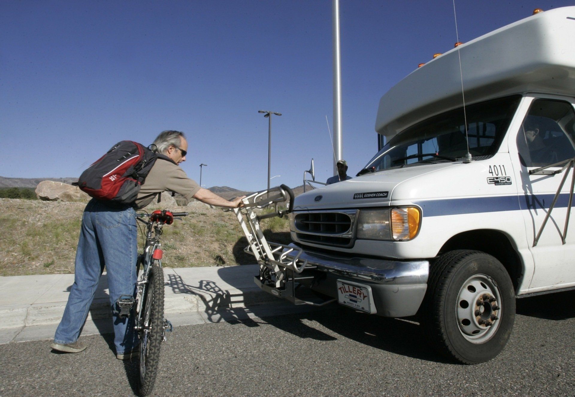 Passenger loading his bicycle on the front of bus Passenger loading his bicycle on the front of bus