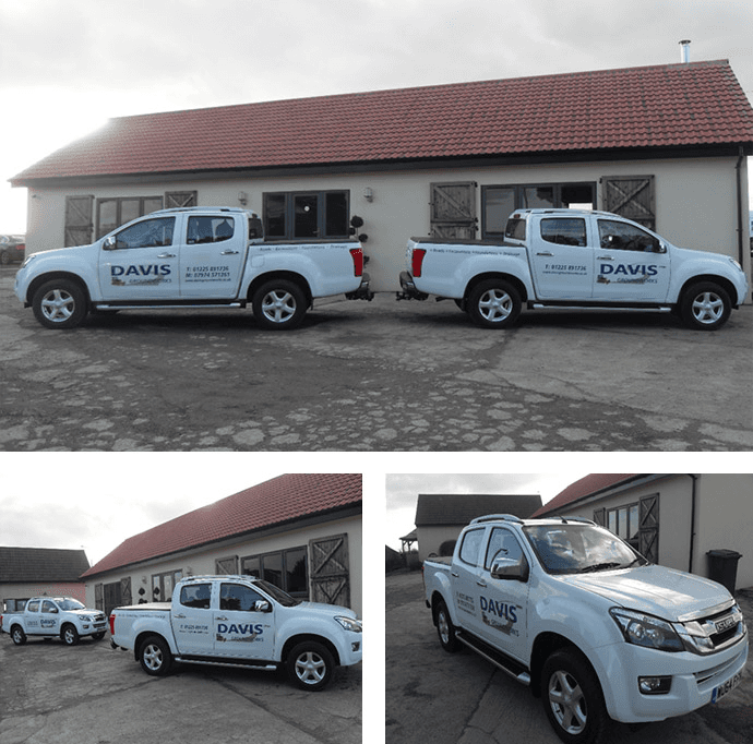 Three white trucks parked near a building with the name