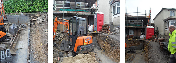 Construction site with mini excavator digging trench next to building; red portable toilet present.