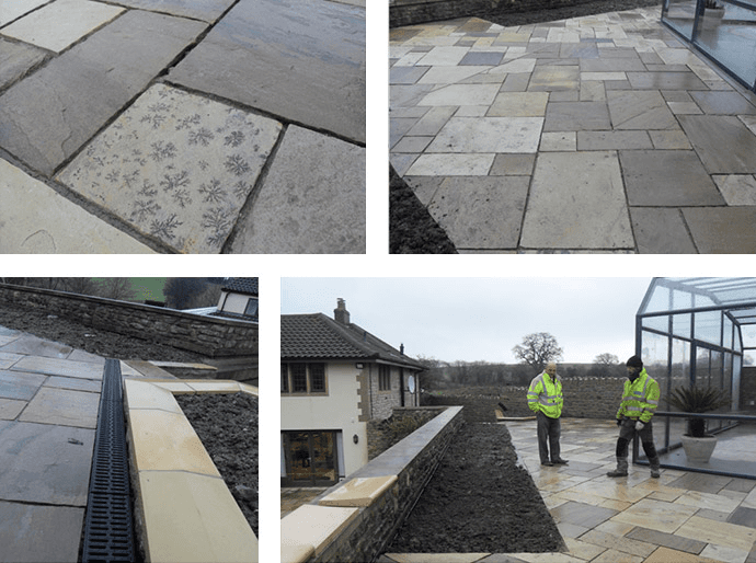 Patio with sandstone pavers, drainage, and workers near a building.
