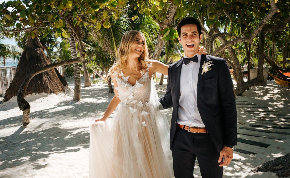 Una novia y un novio posan para una foto en la playa.