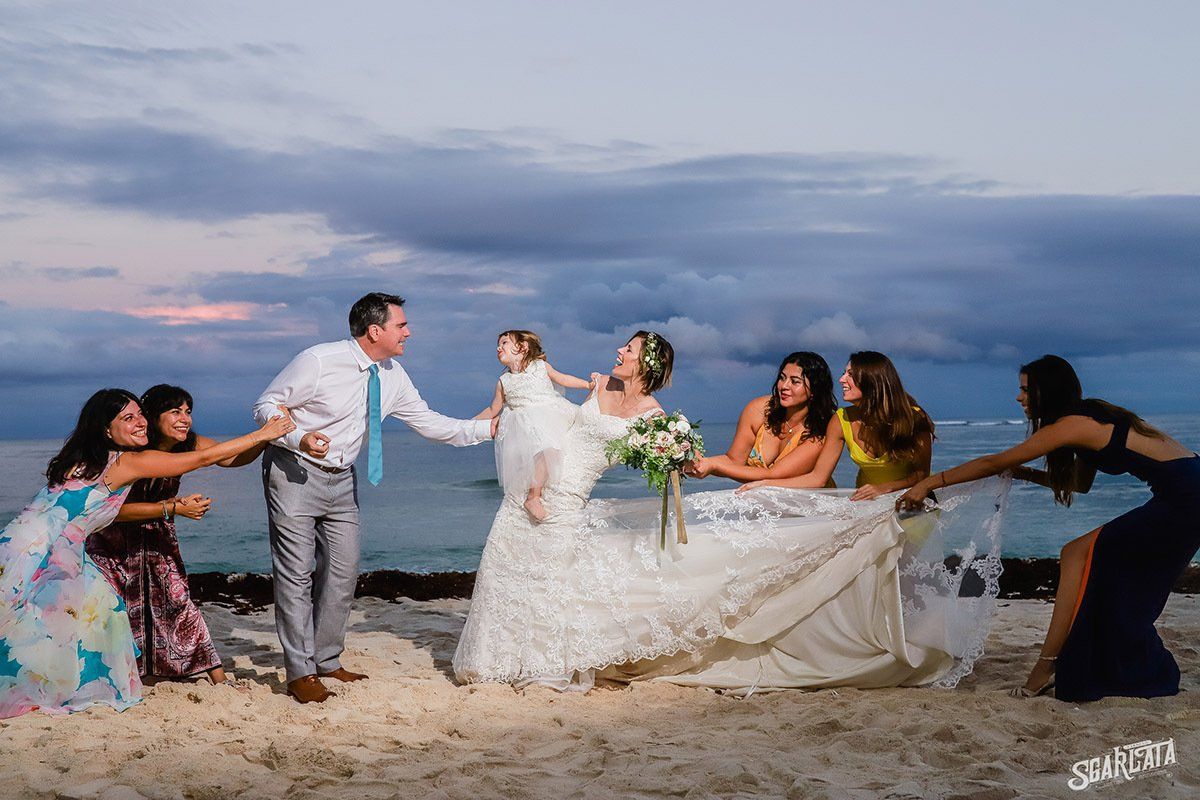 Una novia y un novio posan para una fotografía con su fiesta de bodas en la playa.