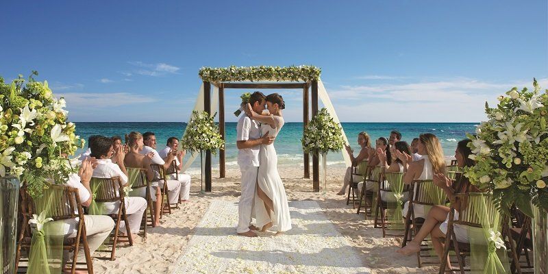 Una novia y un novio están bailando en su ceremonia de boda en la playa.