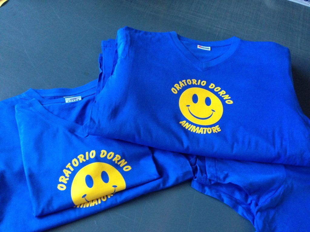 Magliette blu con il logo di una faccina sorridente gialla. La scritta recita 