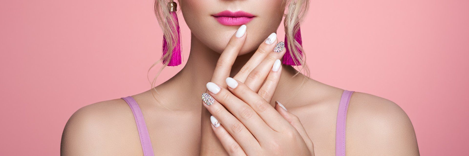 A woman with white nails and pink earrings is covering her face with her hands.