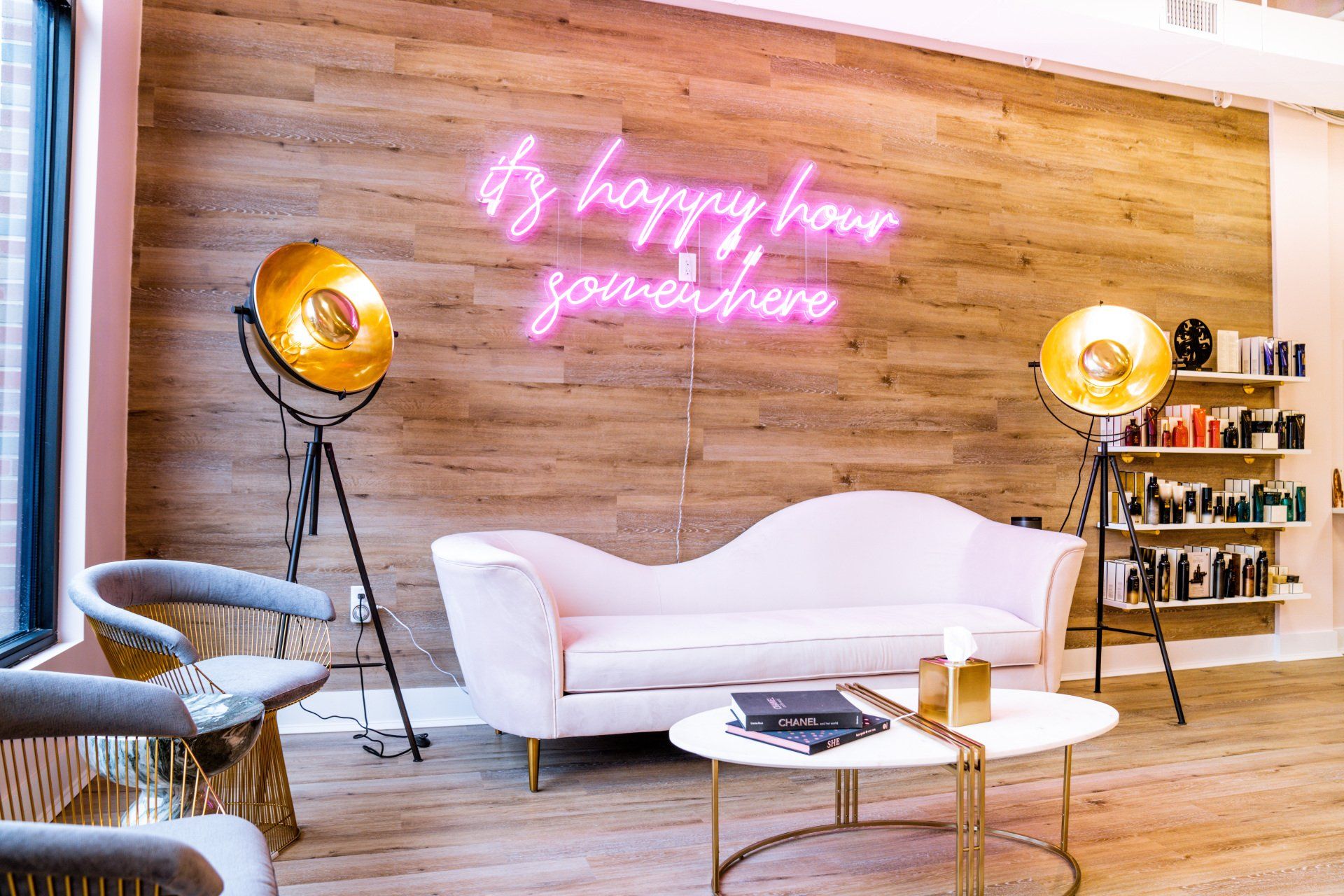 A living room with a couch , table , chairs and a neon sign on the wall.