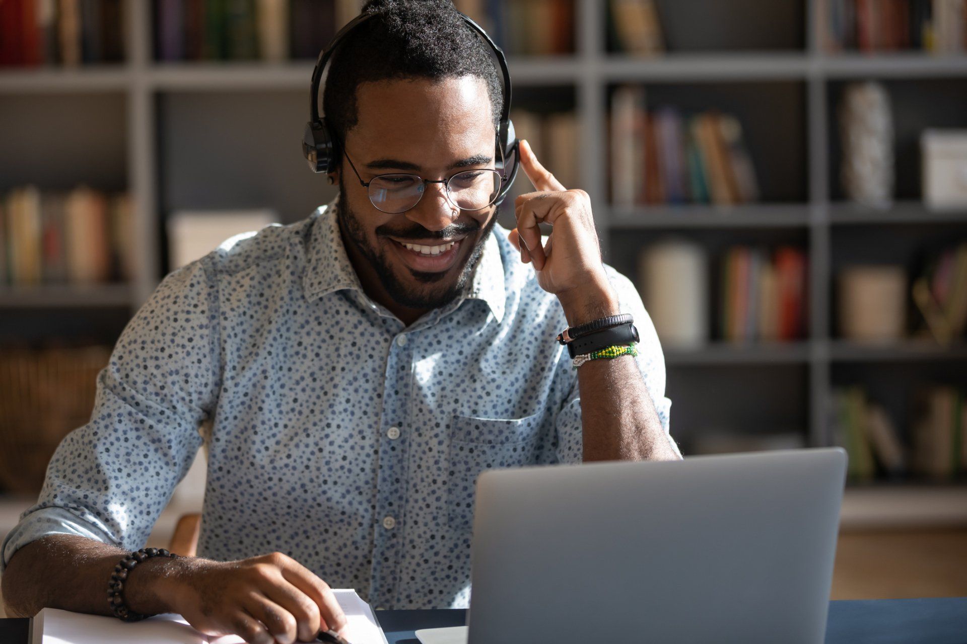 A man wearing headphones is sitting in front of a laptop computer.