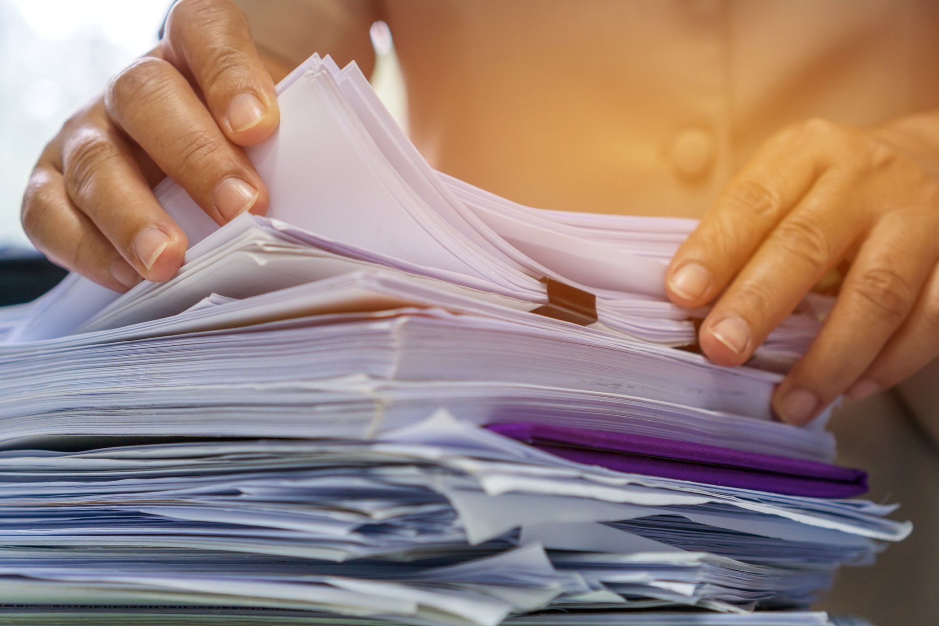 A person is holding a stack of papers in their hands.
