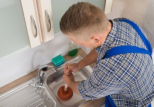 Drain Cleaning — Man cleaning kitchen sink in South Yarmouth, MA Drain Cleaning — Man cleaning kitchen sink in South Yarmouth, MA