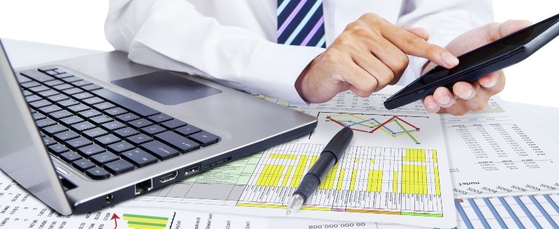 Accountant using calculator while analyzing paperwork