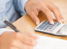 Man using calculator while writing on a piece of paper