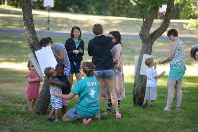 A group of people are standing around a tree in a park.