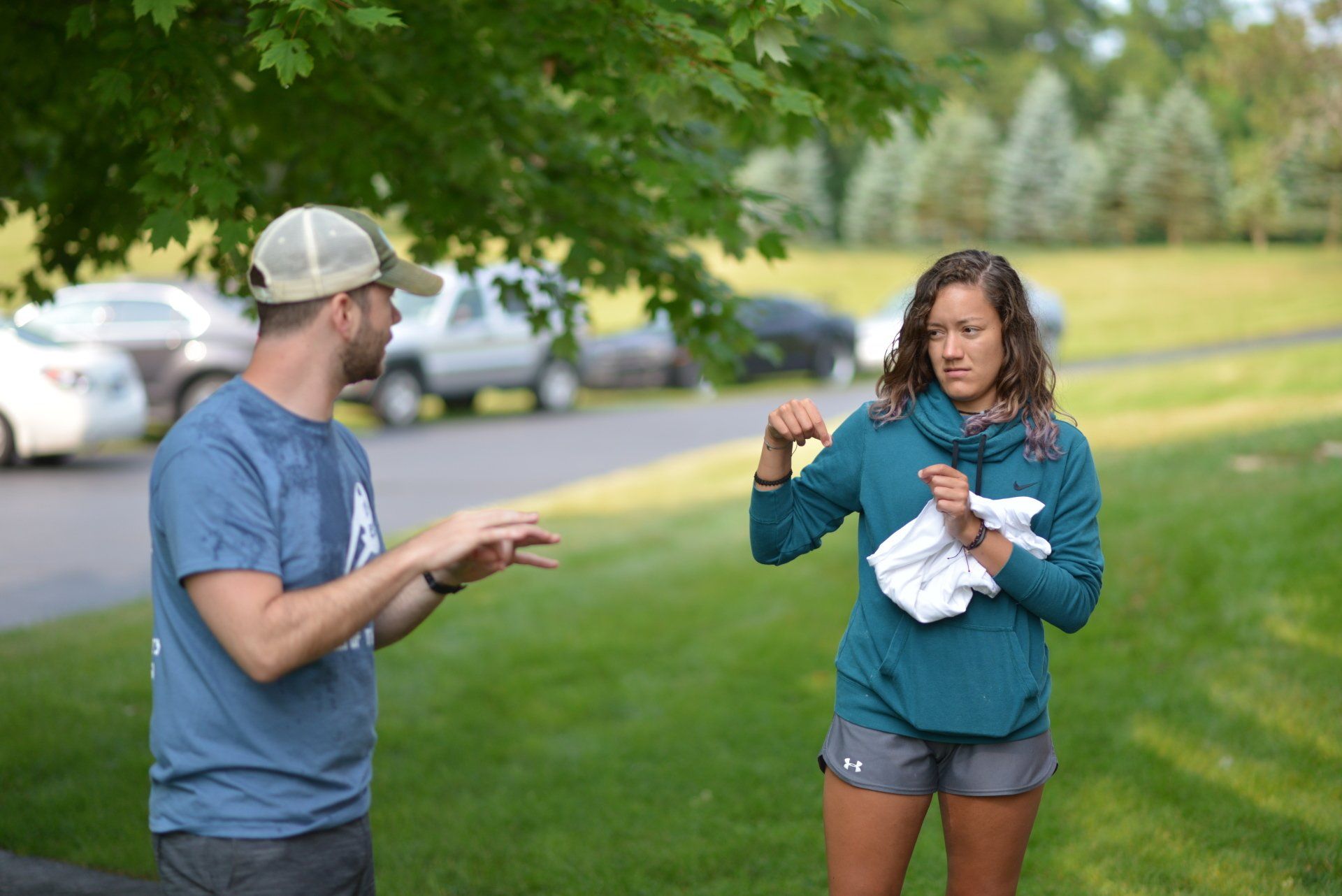 A man and a woman are standing next to each other in a park.