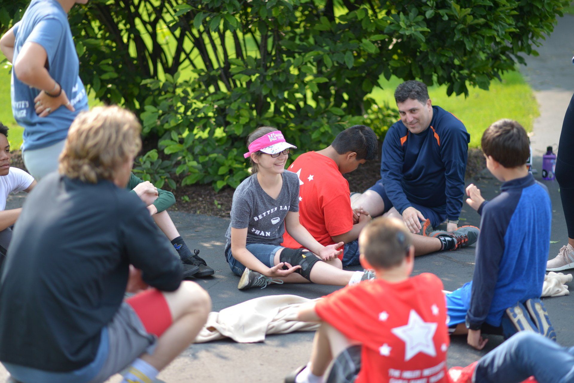 A group of people sitting on the ground with one wearing a red shirt with a star on it