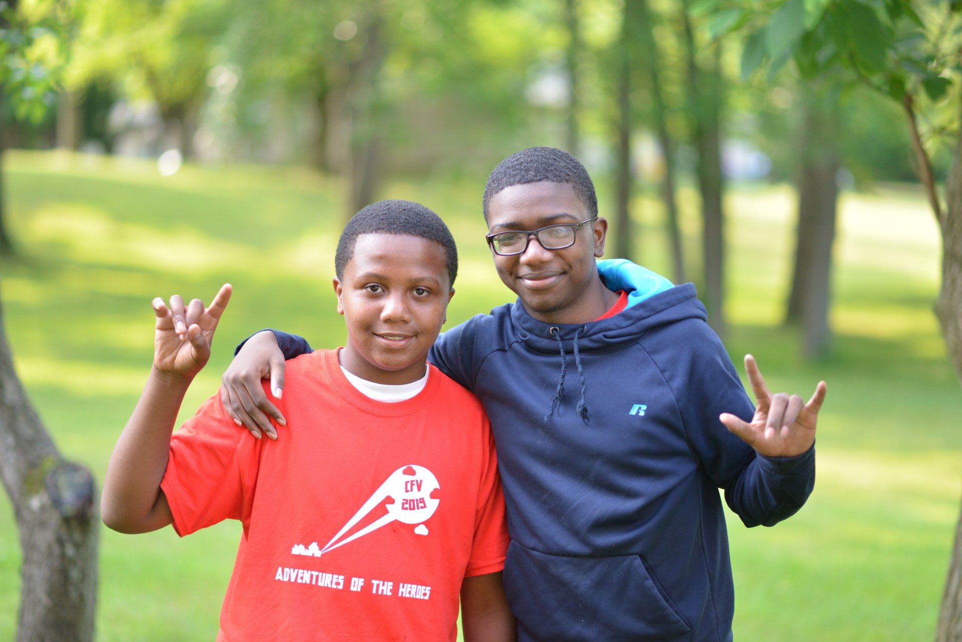 Two young men are posing for a picture in a park.