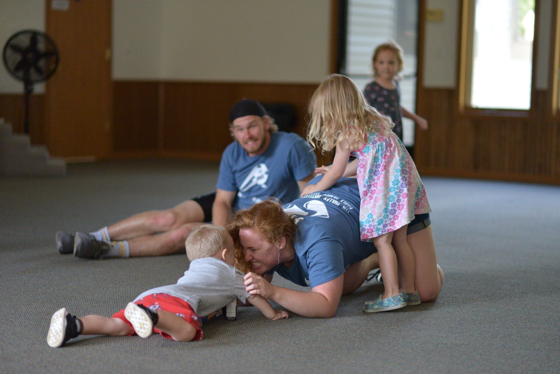 A woman is laying on the floor with two children.