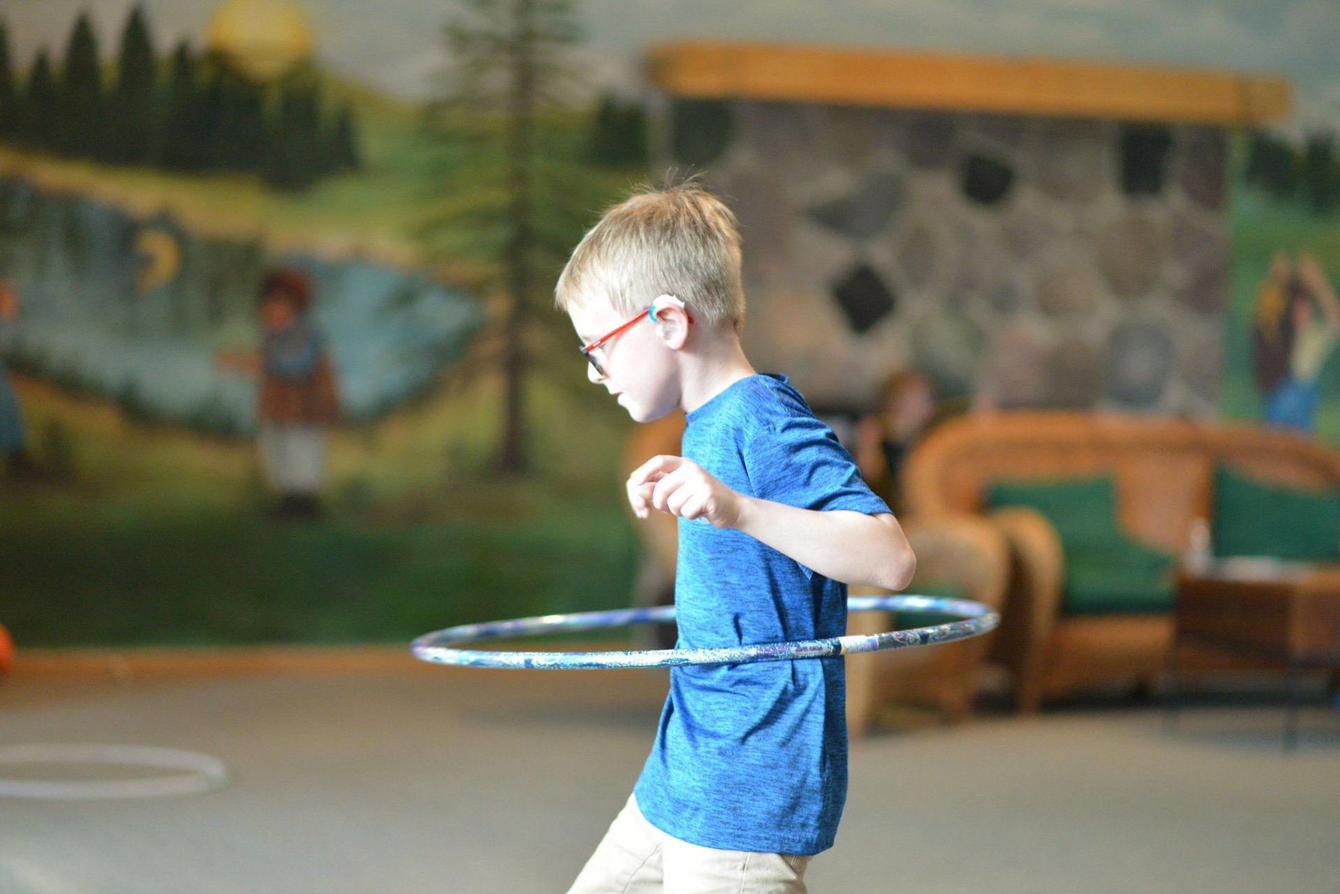 A young boy is playing with a hula hoop in a room.
