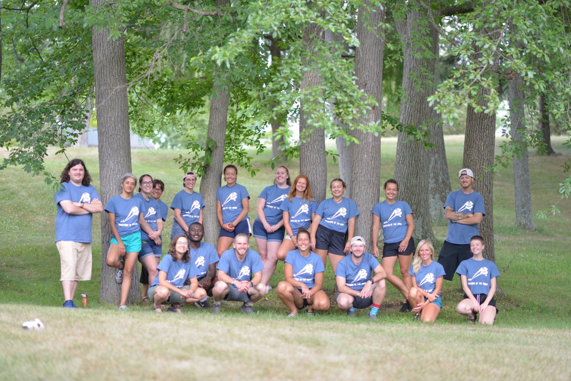 A group of people are posing for a picture in front of trees.